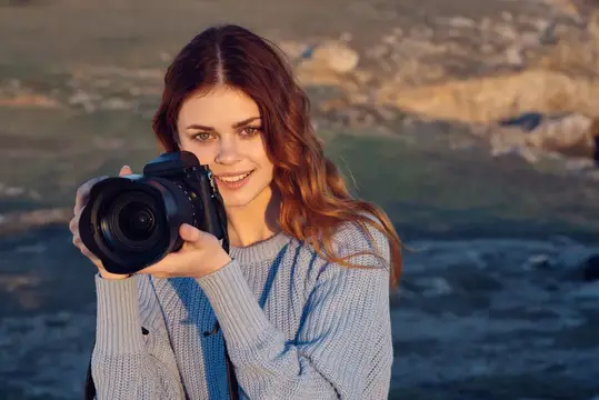 Улыбающаяся девушка с фотокамерой на берегу моря