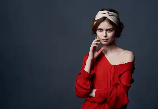 Молодая женщина в красном платье с повязкой на голове на тёмном фоне