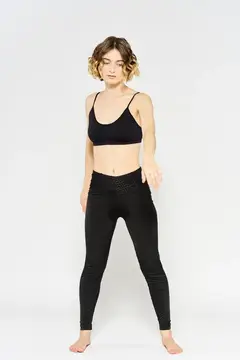 Спортивная женщина в черных джинсах и футболке выполняет упражнения в светлой комнате