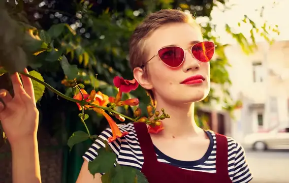 Стриженая девушка в красных очках у цветущего куста