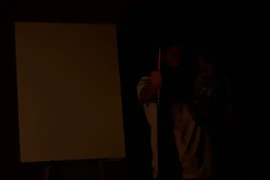 Мужчина рисует на мольберте в тёмной комнате
