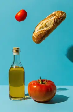 Летящий багет, помидоры и бутылка оливкового масла на синем фоне
