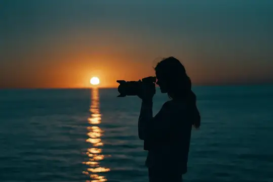 Силуэт девушки с фотоаппаратом на закате у моря