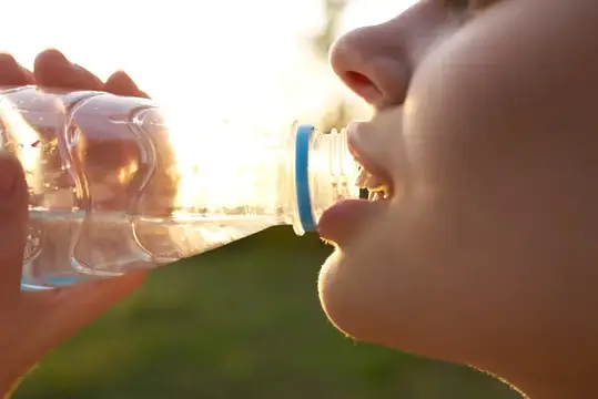 Мальчик пьёт воду из бутылки на закате