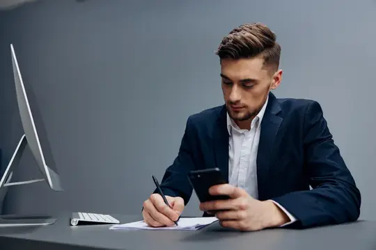 Бизнесмены ведут деловой разговор по телефону, работая перед компьютером на сером фоне