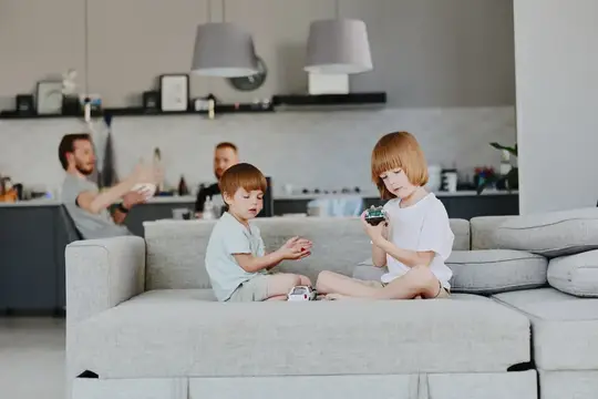Рыжеволосая девочка и мальчик играют на диване в светлой гостиной