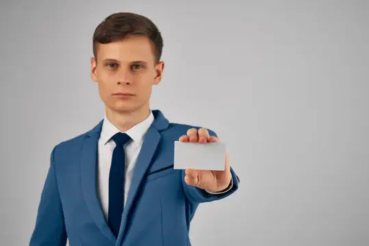 Мужчина в деловом костюме держит в руках визитную карточку и удостоверение личности