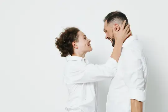 Он стоит прямо, с благодарной улыбкой, в то время как коллега мягко держит его за голову, что символизирует доверие, сотрудничество и лидерство на минималистичном цветовом поле, подчеркивающем…