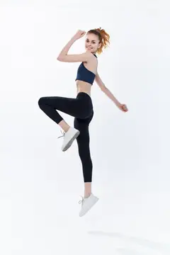 Молодая женщина в спортивной форме прыгает с поднятой ногой