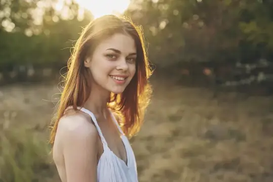 Красивая женщина в белом платье идет по полю, наслаждаясь свежим воздухом летом