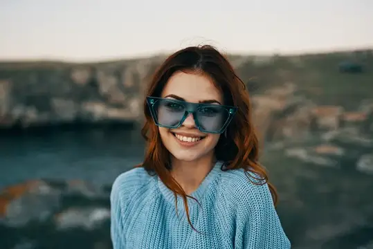 Улыбающаяся девушка в солнцезащитных очках на фоне моря