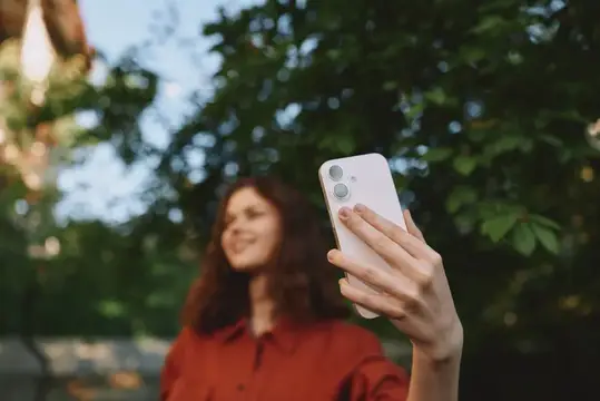 Улыбающаяся женщина делает селфи на смартфон в парке