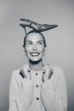 Улыбающаяся женщина с туфлей на голове в студии