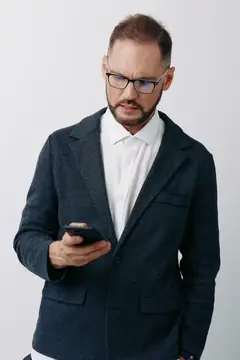 Мужчина в очках и тёмном пиджаке смотрит в телефон