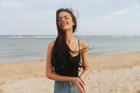 Счастливая женщина бежит по пляжу на закате