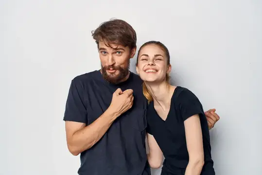Бородатый мужчина и смеющаяся девушка в чёрных футболках на светлом фоне