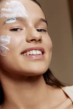 Улыбающаяся девушка с косметической маской на лице