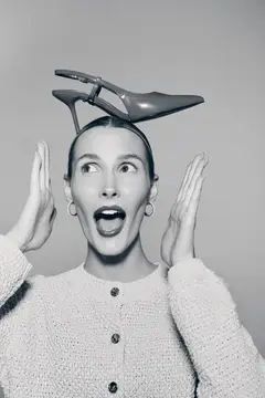 Удивлённая женщина с туфлей на голове вскинула руки