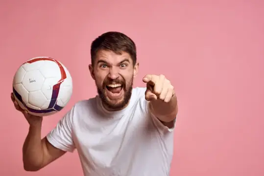 Мужчина с футбольным мячом на розовом фоне