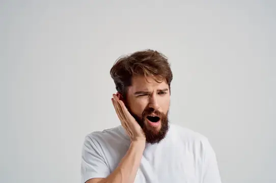 Эмоциональный мужчина с зубной болью на светлом фоне