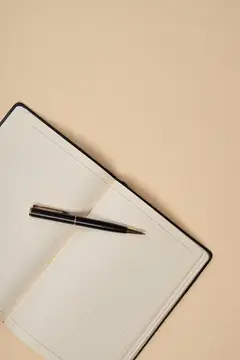 Открытый блокнот с ручкой на бежевом фоне