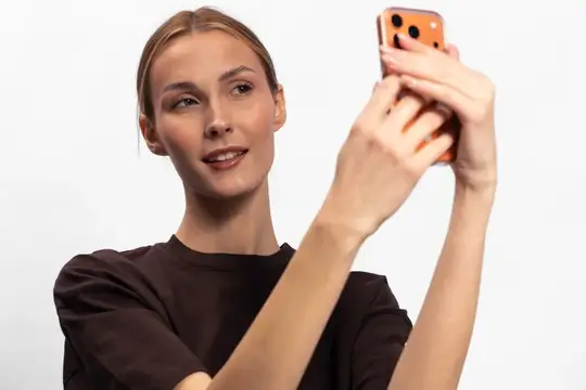 Молодая женщина делает селфи на смартфон на белом фоне