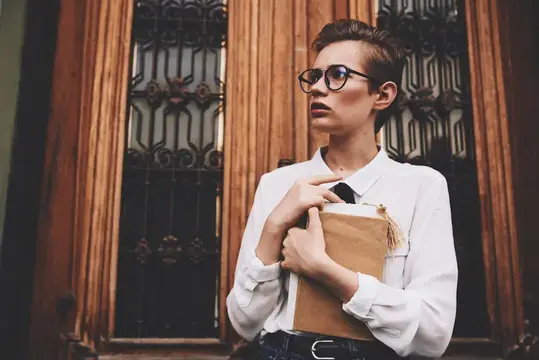 Студент с книгой в руках на открытом воздухе, читает на фоне природы