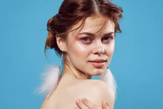 Молодая женщина с пушистыми серьгами на голубом фоне
