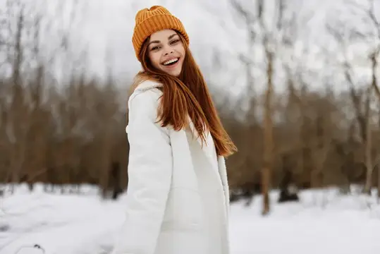 Женщина в зимней одежде и шапке на фоне весёлого зимнего пейзажа