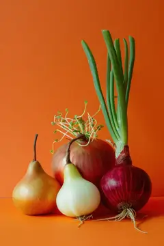 Красный лук, зелёный лук и две груши на оранжевом фоне