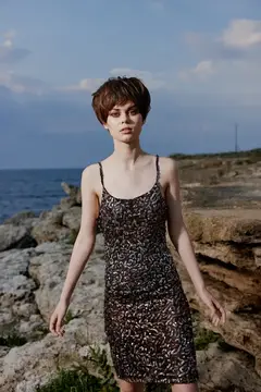 Молодая женщина с короткой стрижкой стоит на скалах у моря