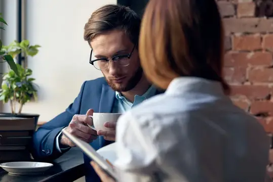 Мужчина и женщина, коллеги по работе, общаются, весело проводят досуг в кафе