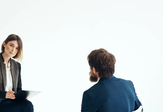 Женщина с планшетом смотрит на бородатого мужчину в белой студии