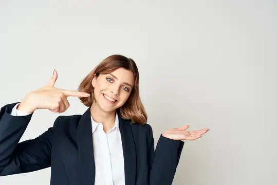 Улыбающаяся шатенка в деловом костюме жестом показывает в сторону
