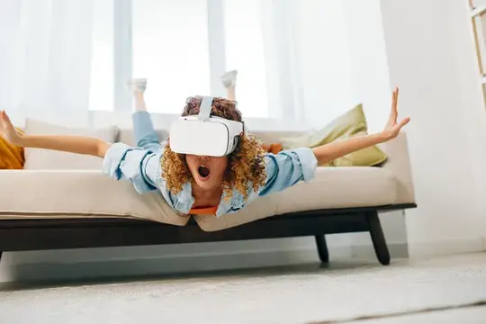 Улыбающаяся женщина в современных VR-очках в гостиной, радость от виртуальной реальности