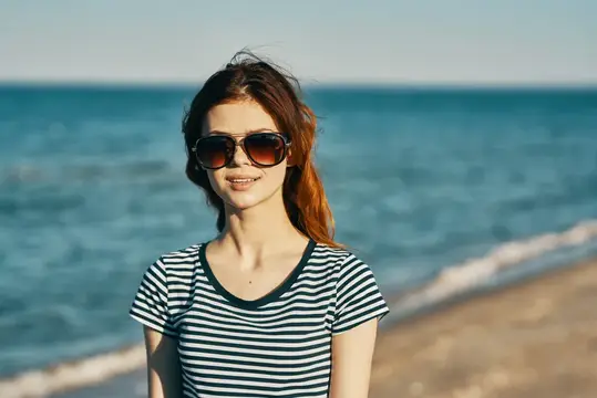 Улыбающаяся девушка в солнцезащитных очках на фоне моря