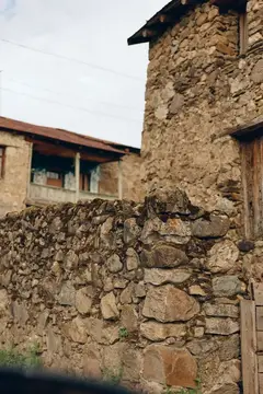 Старая каменная стена и дом из грубого камня в горной деревне