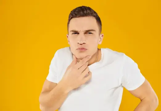 Задумчивый парень в белой футболке на жёлтом фоне
