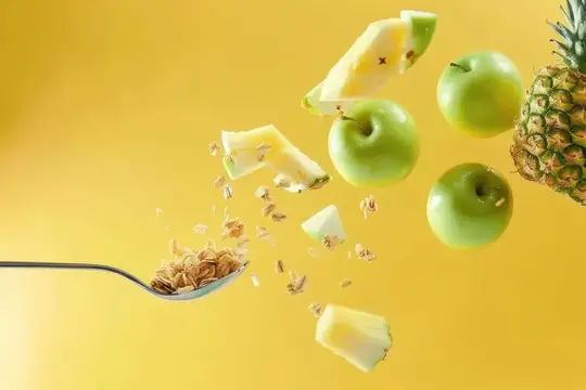 Свежие фрукты падают с ложки на яркий желтый фон