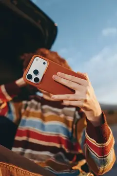 Рыжеволосая девушка фотографирует на смартфон у открытого багажника