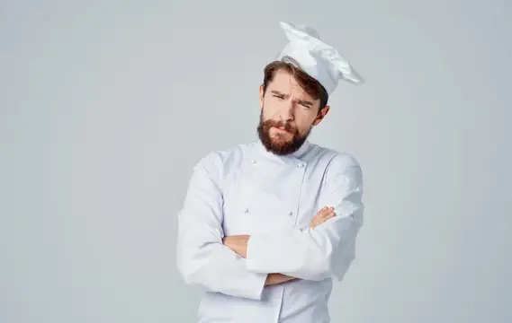 Бородатый повар в белом колпаке со скрещёнными руками