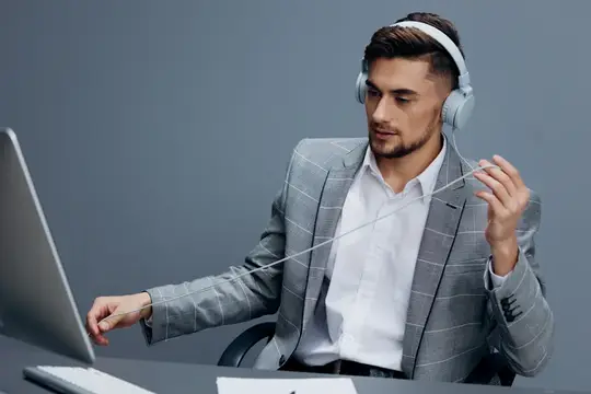 Молодой мужчина в наушниках работает за ноутбуком в офисе