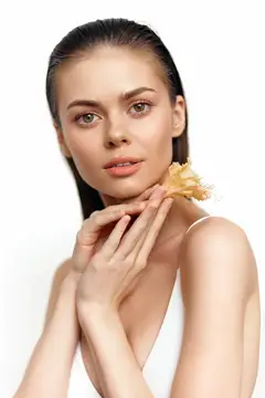 Молодая женщина с цветком у лица на белом фоне