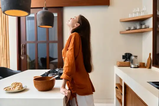 Молодая женщина с закрытыми глазами отдыхает на светлой кухне
