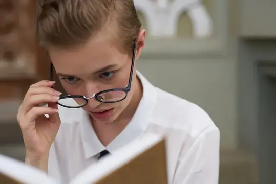 Мальчик в очках внимательно читает книгу