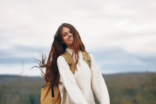 Улыбающаяся девушка с рюкзаком на фоне пасмурного неба