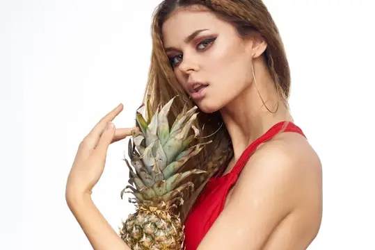 Молодая женщина с ананасом в руке на белом фоне