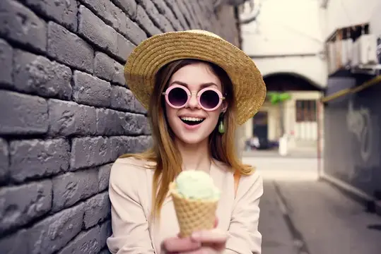 Улыбающаяся девушка в соломенной шляпе и круглых очках с мороженым