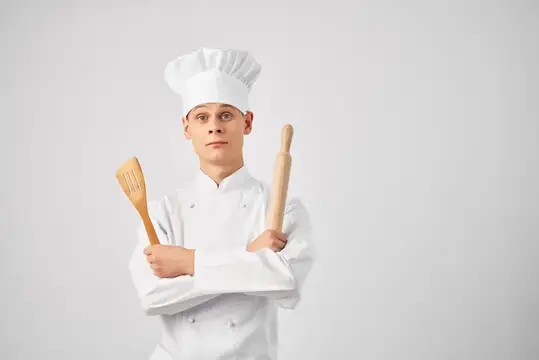 Мужчина-повар профессионально занимается приготовлением пищи на кухне на светлом фоне