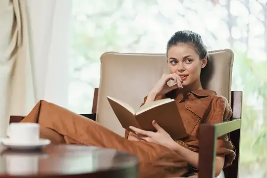 Молодая женщина с книгой в уютном кресле у окна